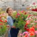 Woman in a greenhouse. Lady works with flowerpoots. Girl in a black apron.