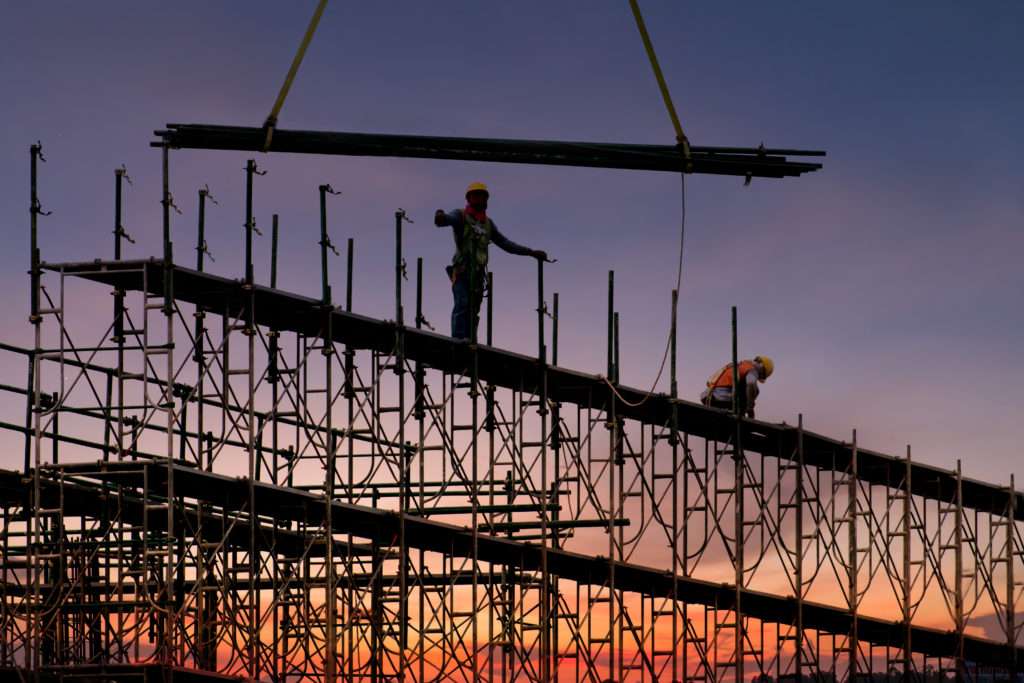 Man working on construction site with scaffold and building with