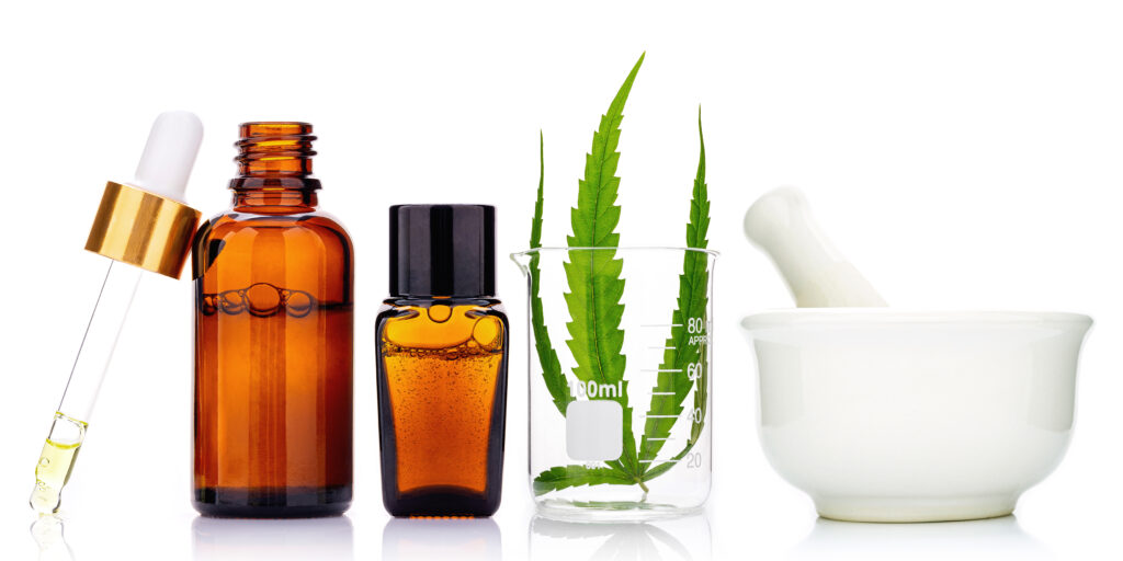 Glass bottles of cannabis oil and hemp leaves isolated on white
