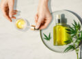 Pipette with CBD cosmetic oil in female hands on a table background with a bottle of cannabis oil and hemp leaves, marijuana